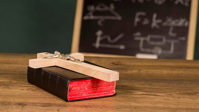 A crucifix on a book against the background of a chalkboard 