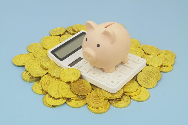 Piggy bank and calculator on heap of gold coins 