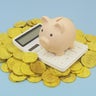 Piggy bank and calculator on heap of gold coins 