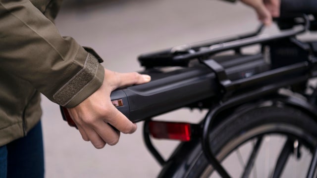 Woman fitting battery on electric bike 