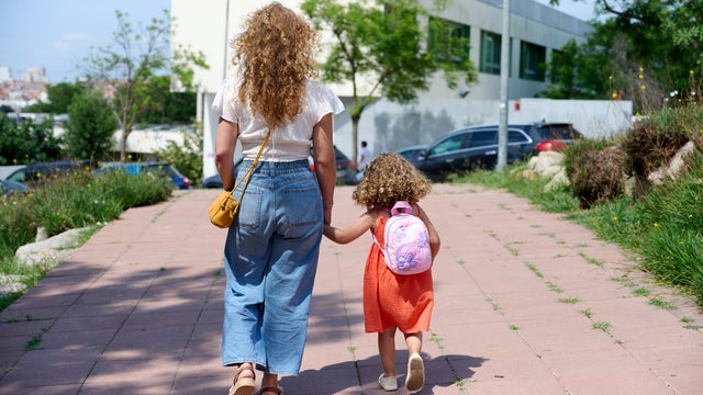 Mother walking daughter to school on a sunny day 