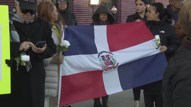People hold white roses, Dominican flag 