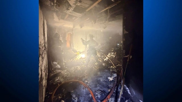 A firefighters stands in the middle of a room that has been damaged by a fire 