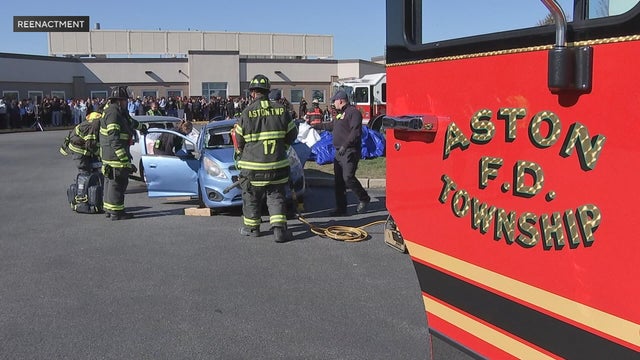 Firefighters at the scene of the mock crash at Sun Valley High School as students look on 