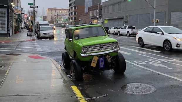 Green mini monster truck parked on street 