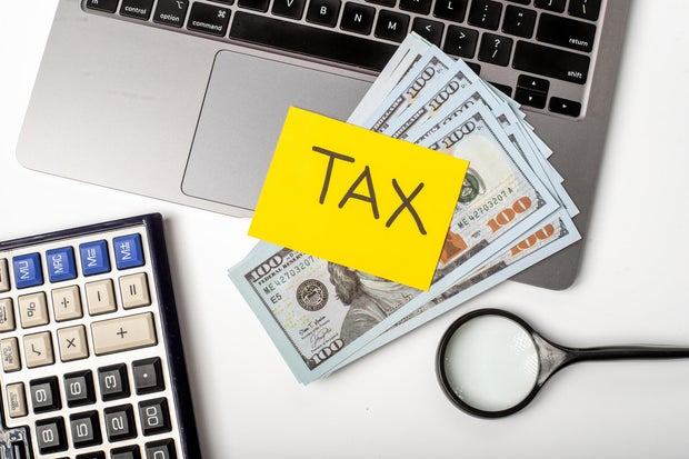 Handling finances while preparing for tax season with cash and tools on a desk 