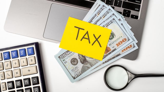 Handling finances while preparing for tax season with cash and tools on a desk 