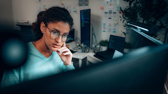 Young Latina programmer coding at computer in tech office 