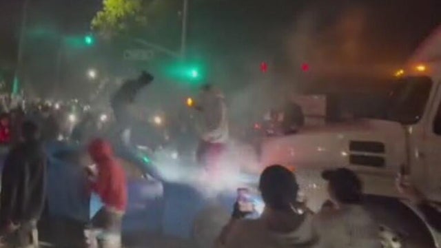 People jumping on a vehicle that has crashed into a semitruck 