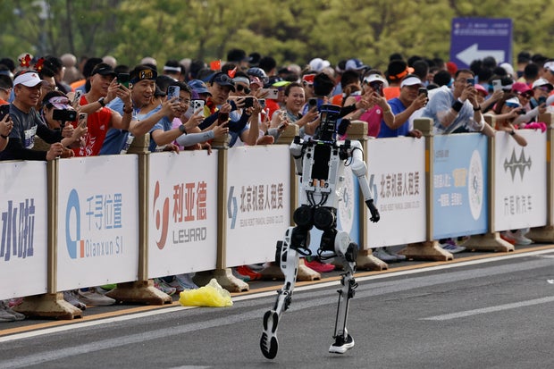 Runners participating in the second Beijing E-Town Half Marathon take pictures of the Tiangong Ultra 2026 humanoid robot participating in the Humanoid Robot Half Marathon in Beijing, China, April 19, 2026. 