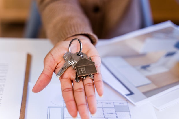 Person holding new house keys and home plans 