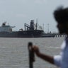 A man looks at India-flagged tanker Desh Garima, as it unloads crude oil at an offloading terminal after transiting the Strait of Hormuz, amid supply disruptions linked to the U.S.-Israeli conflict with Iran, in Mumbai 