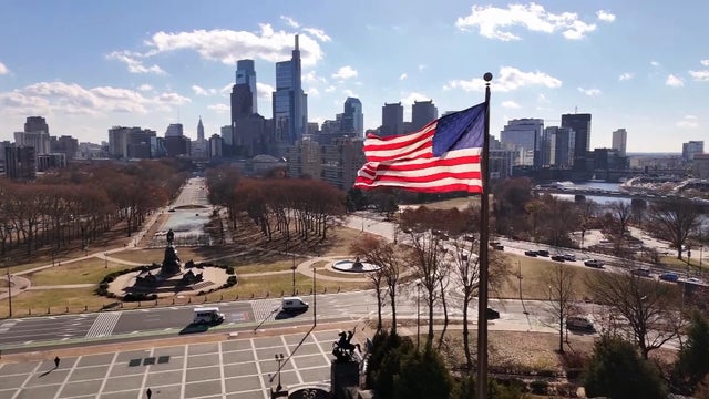Drone video from near the art museum, a flag and the skyline are visible, as is the Benjamin Franklin Parkway 