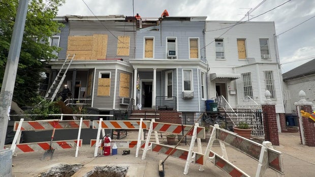 Exterior of three homes with windows boarded up 