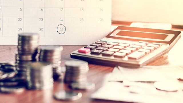debt collection and tax season concept with deadline calendar remind note,coins,banks,calculator on table 