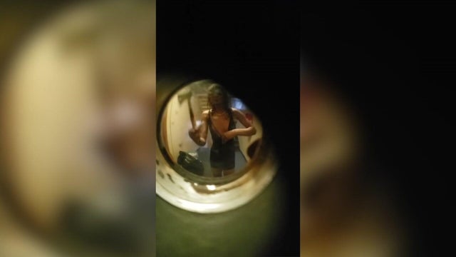 View of individual holding a hatchet through a peephole 