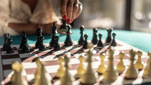 A woman starts a chess game with the first move of a pawn 