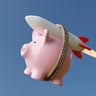 Pink piggy bank carried by a rocket in clear blue sky. Illustration of the concept of skyrocketing prices of stocks and other investment 