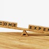 3D income vs expenses on balance scales. Living paycheck to paycheck. High income with low expenses. Financial problems, monthly expenses, inflation, debt or loan concept 