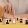 Selection of people to work in the company ,Managers choose people to do the right job for the job ,People symbol on wooden block ,Finger points to the correct option ,Different from others. 