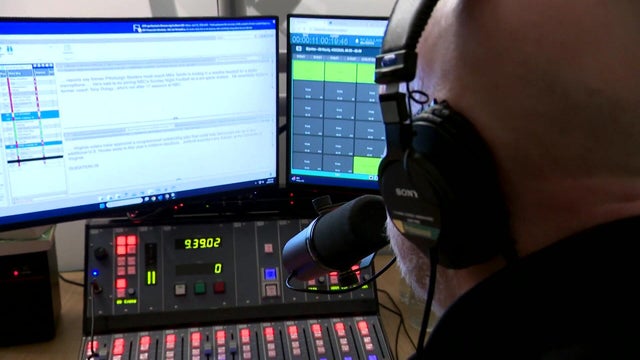 Man at microphone in front of computers 