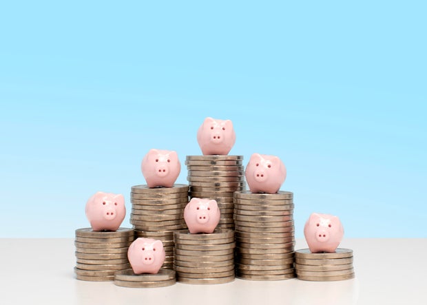 Savings concept - 7 piggy banks on 7 piles of US nickel coins 