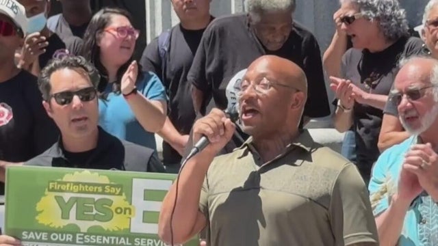 a speaker at a rally stands in front of a crowd 