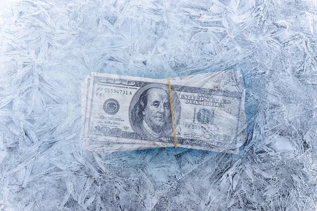 mixed image of frozen dollars in ice cube, global economic crisis and downsizing concepts 