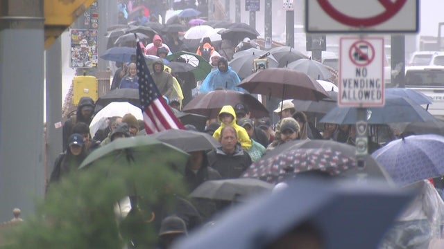 People carrying umbrellas cross the Brooklyn Bridge 