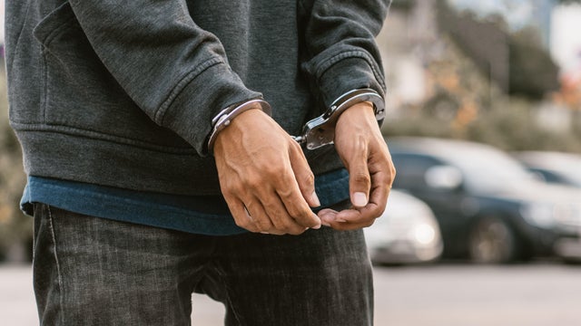 Save to BoardLooking down at handcuffed male hands on black background 