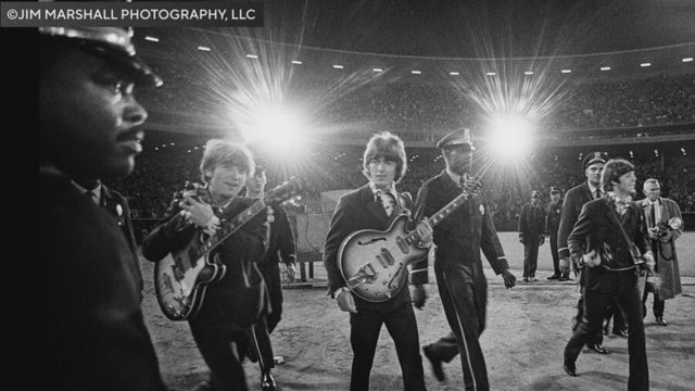stadium lights shine behind members of the beatles 