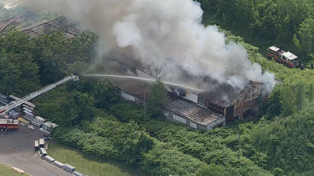 Smoke is seen coming from a warehouse in Camden, fire crews are shooting water 