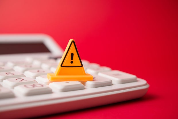 Yellow warning sign on white calculator with red background copy space.