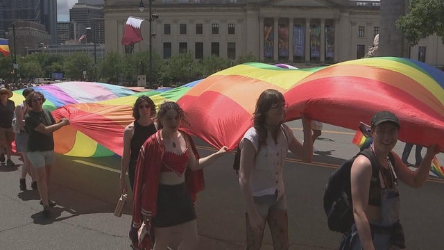 People carry the Pride flag along the Benjamin Franklin Parkway 