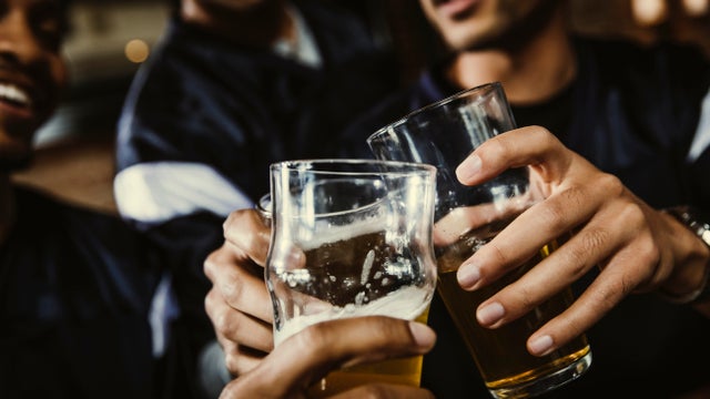 Cropped image of male soccer fans toasting beer glasses in bar 