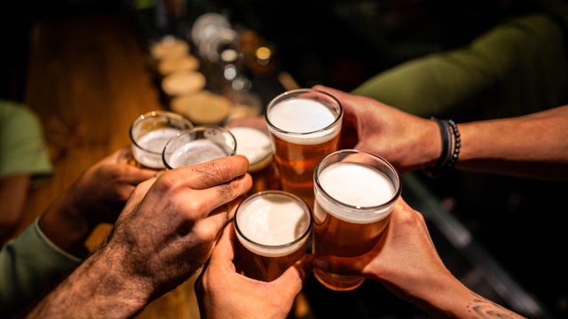Close-up of a friends toasting with beers on a bar 