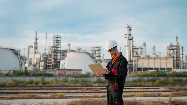 Service engineer is working with laptop in power plant at twilight 