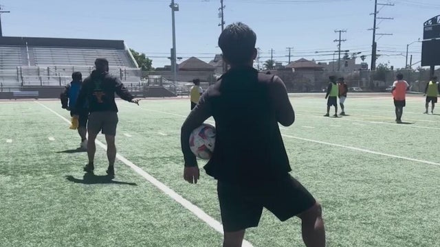 a person holding a soccer ball looking at other players on the pitch 