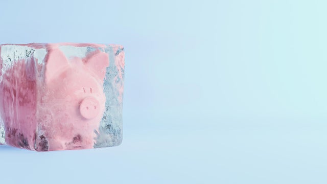 Pink piggy bank frozen in ice cube, frozen account concept, flat blue background, 3D Render 