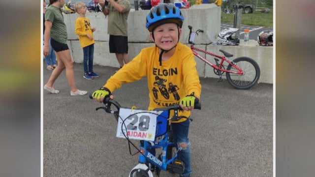 Aidan smiles while riding his bike 