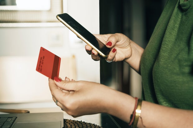Woman completing an online payment using a mobile phone and bank card