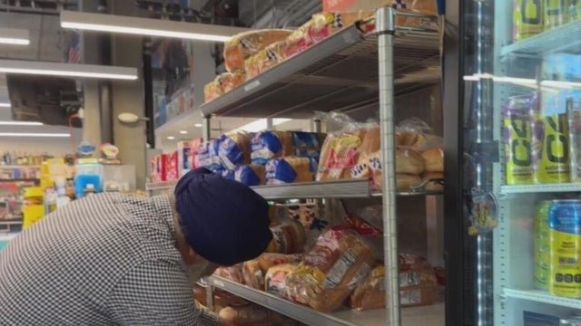 A man organizes a shelf at a grocery store 