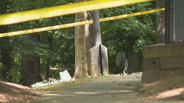 Police tape and debris are seen at the site of a small plane crash in a park in Maryland 