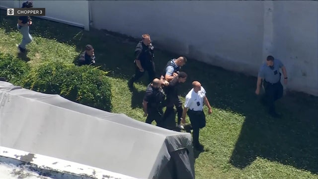 Police surround a suspect near a black shed in a backyard in Bridesburg 