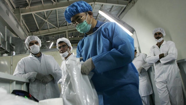 Iranian technicians look at an inspector 