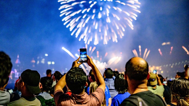 Spectators view and take photos during the New York City Macy's fireworks display celebrating the United States' 249th independence day at Brooklyn Bridge Park on July 04, 2025 in New York City. 
