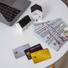 Small house with the dollar bills, credit card and transparent clock background. concept of the home payment interest of house loan monthly installment. Finance and Real Estate Investment. 