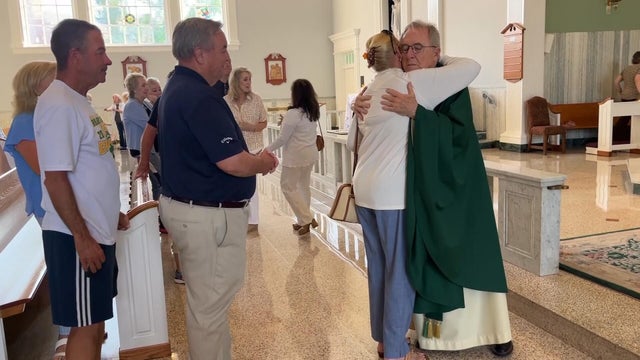 Father Michael Murphy hugs someone in the church after his final Mass at St. Dorothy 