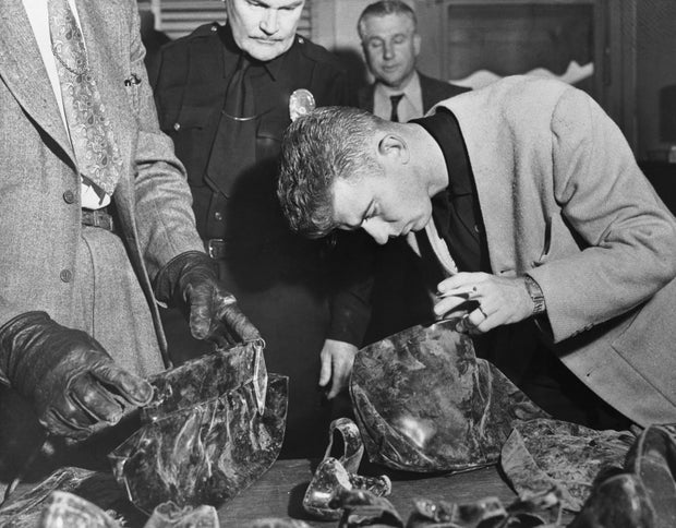 Man Inspecting Purses at Police Station
