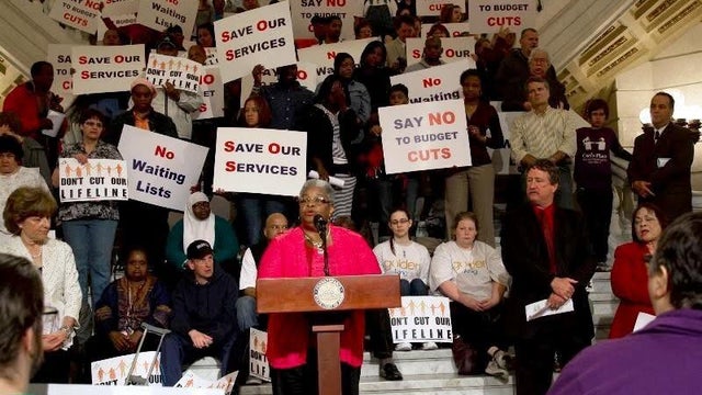 State Sen. Shirley Kitchen speaks at an event at the capitol, surrounded by supporters holding signs 